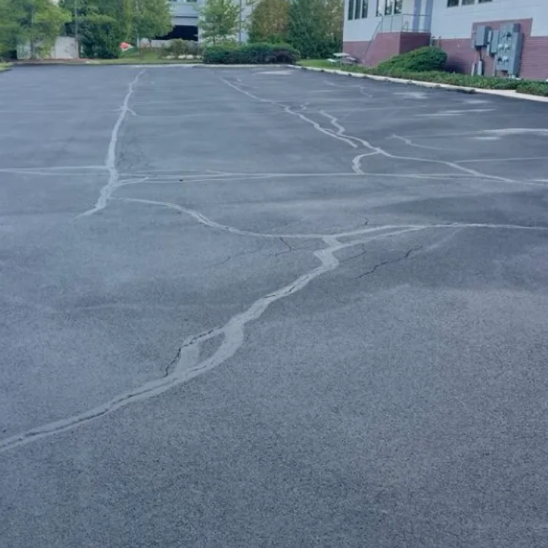 A driveway is being widened with a new strip of asphalt on one side.